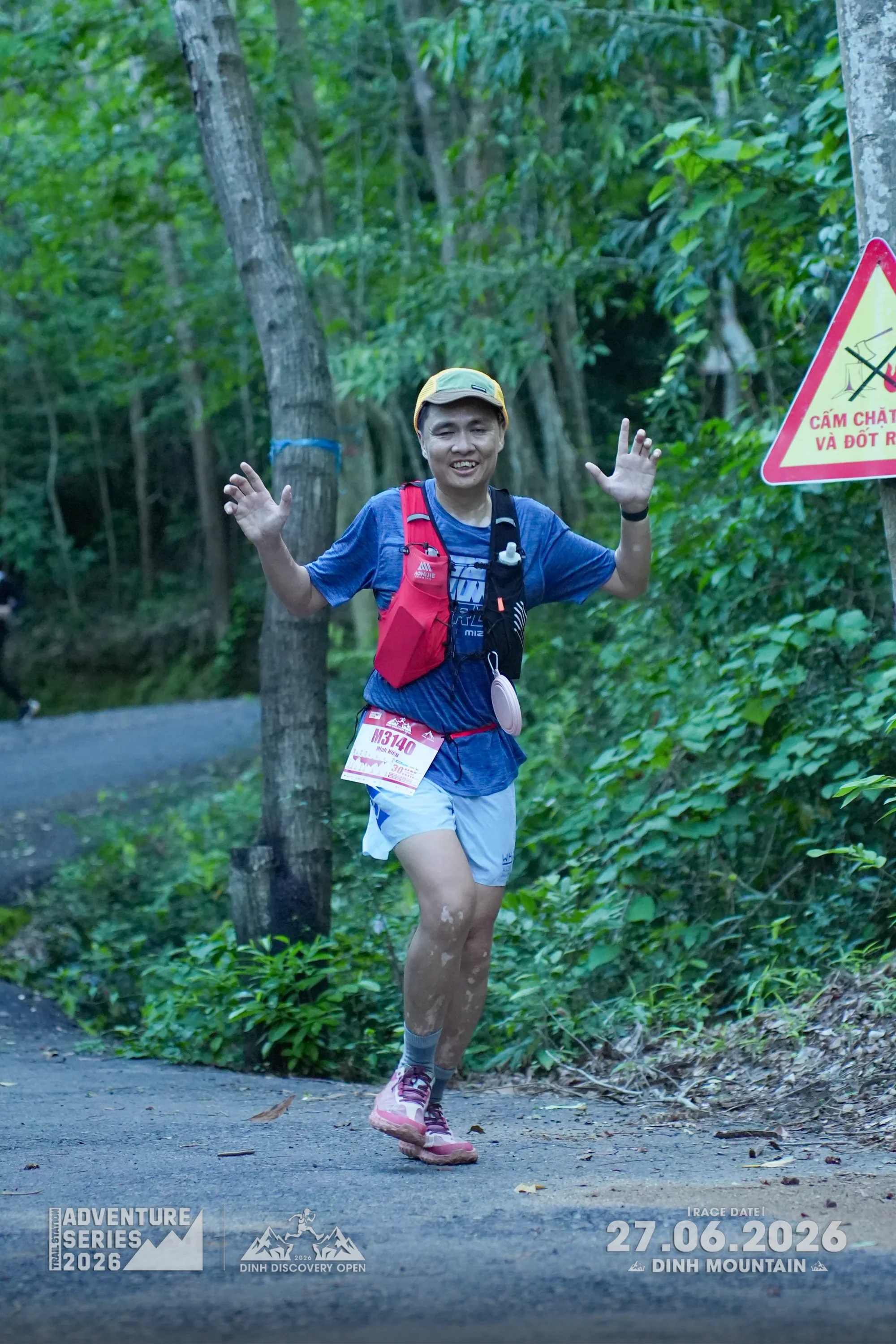 Runner celebrating with hands up on the trail